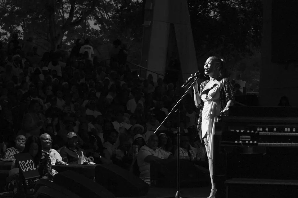 A vocalist performs to a rapt audience, photographed in black and white