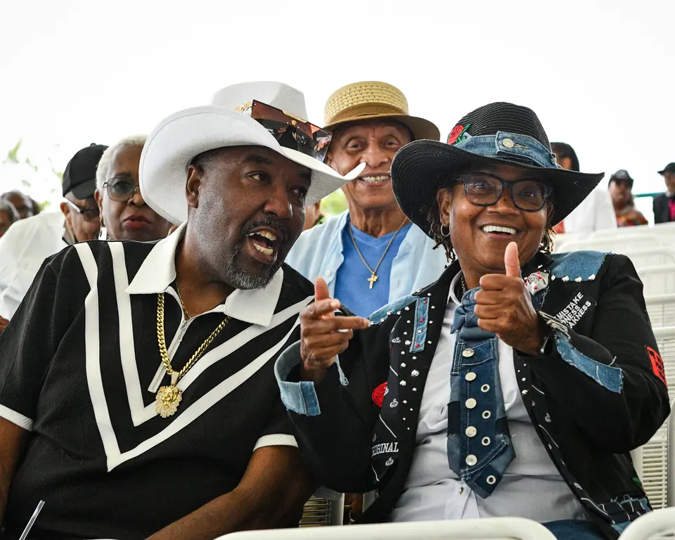 Two guests in statement hats laughing in their seats
